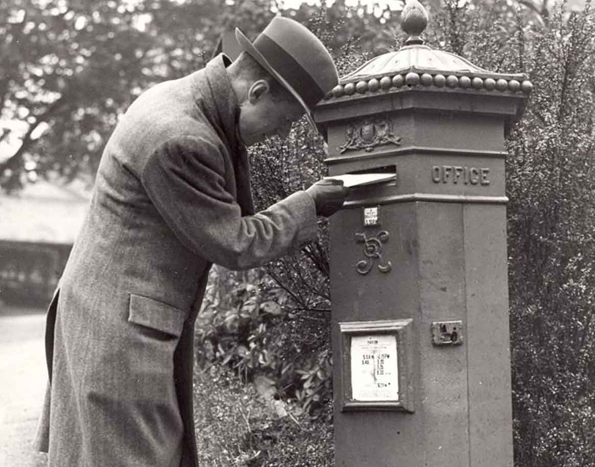 man posting a letter into ER postbox to illustrate The Postal Book Club